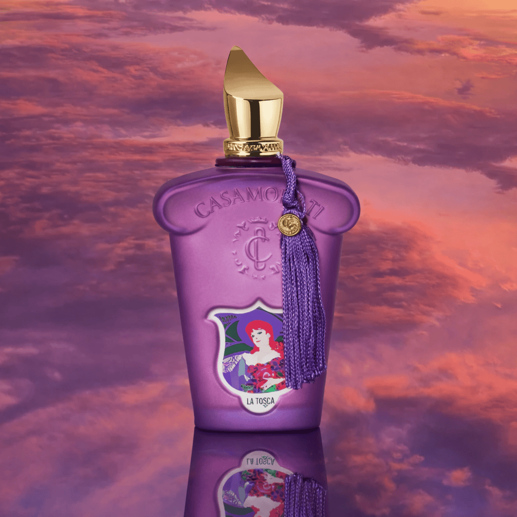 Azúrkék Casamorati La Tosca parfüm üveg, arany kupakkal, naplementés ég alatt, luxus illatszer.